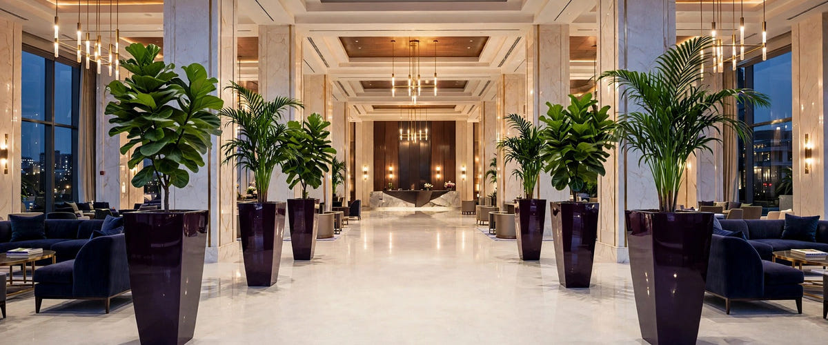 Jay Scotts tall tapered square fiberglass planters in a gloss eggplant finish lining a luxury hotel lobby