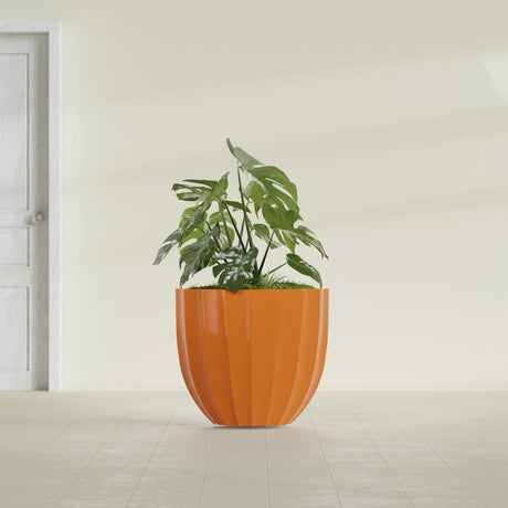 Santa Barbara Fluted Round fiberglass planter in Gloss Tangerine, shown planted, in a sunlit interior