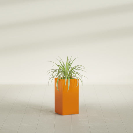 Hollywood Corner fiberglass planter in Gloss Tangerine, shown planted, in a sunlit interior