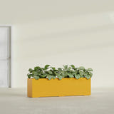 Hudson Extra Long fiberglass planter in Gloss Saffron, shown planted, in a sunlit interior