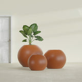 Globe fiberglass planter in Matte Terra Cotta, size range, in a sunlit interior