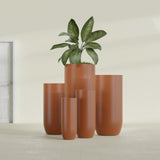 Saint Tropez Bullet Round fiberglass planter in Matte Terra Cotta, size range, in a sunlit interior