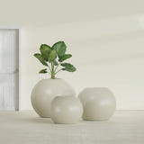 Globe fiberglass planter in Satin Beige, size range, in a sunlit interior