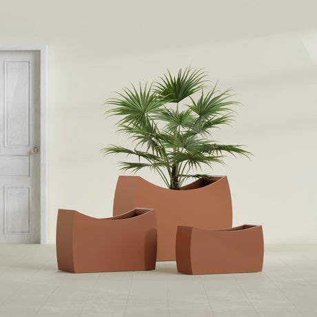 Seoul Curved fiberglass planter in Matte Terra Cotta, size range, in a sunlit interior