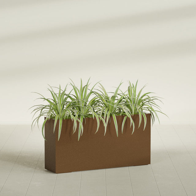 Hollywood Narrow fiberglass planter in Metallic Bronze, planted, in a sunlit interior