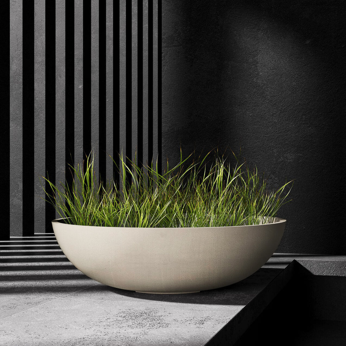 Cavo low bowl Cosapots fiberglass planter, shown planted with ornamental grasses in a styled setting.