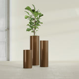 Corry Cylinder fiberglass planter in Metallic Bronze, size range, in a sunlit interior