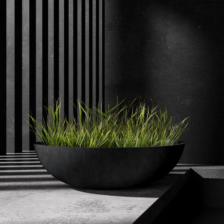 Cavo low bowl Cosapots fiberglass planter, shown planted with ornamental grasses in a styled setting.