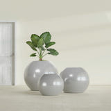 Globe fiberglass planter in Metallic Silver, size range, in a sunlit interior