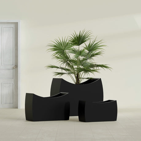 Seoul Curved fiberglass planter in Matte Black, size range, in a sunlit interior