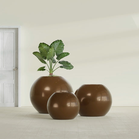 Globe fiberglass planter in Metallic Bronze, size range, in a sunlit interior
