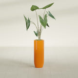 Saint Tropez Bullet Round fiberglass planter in Gloss Tangerine, shown planted, in a sunlit interior