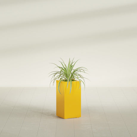 Hollywood Corner fiberglass planter in Gloss Saffron, shown planted, in a sunlit interior