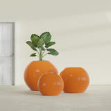 Globe fiberglass planter in Gloss Tangerine, size range, in a sunlit interior