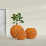 Globe fiberglass planter in Gloss Tangerine, size range, in a sunlit interior