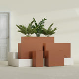 Potsdam Corner fiberglass planter in Matte Terra Cotta, size range, in a sunlit interior