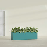 Hudson Extra Long fiberglass planter in Satin Seafoam Green, shown planted, in a sunlit interior