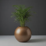 Globe fiberglass planter in Metallic Bronze, planted with an areca palm, studio