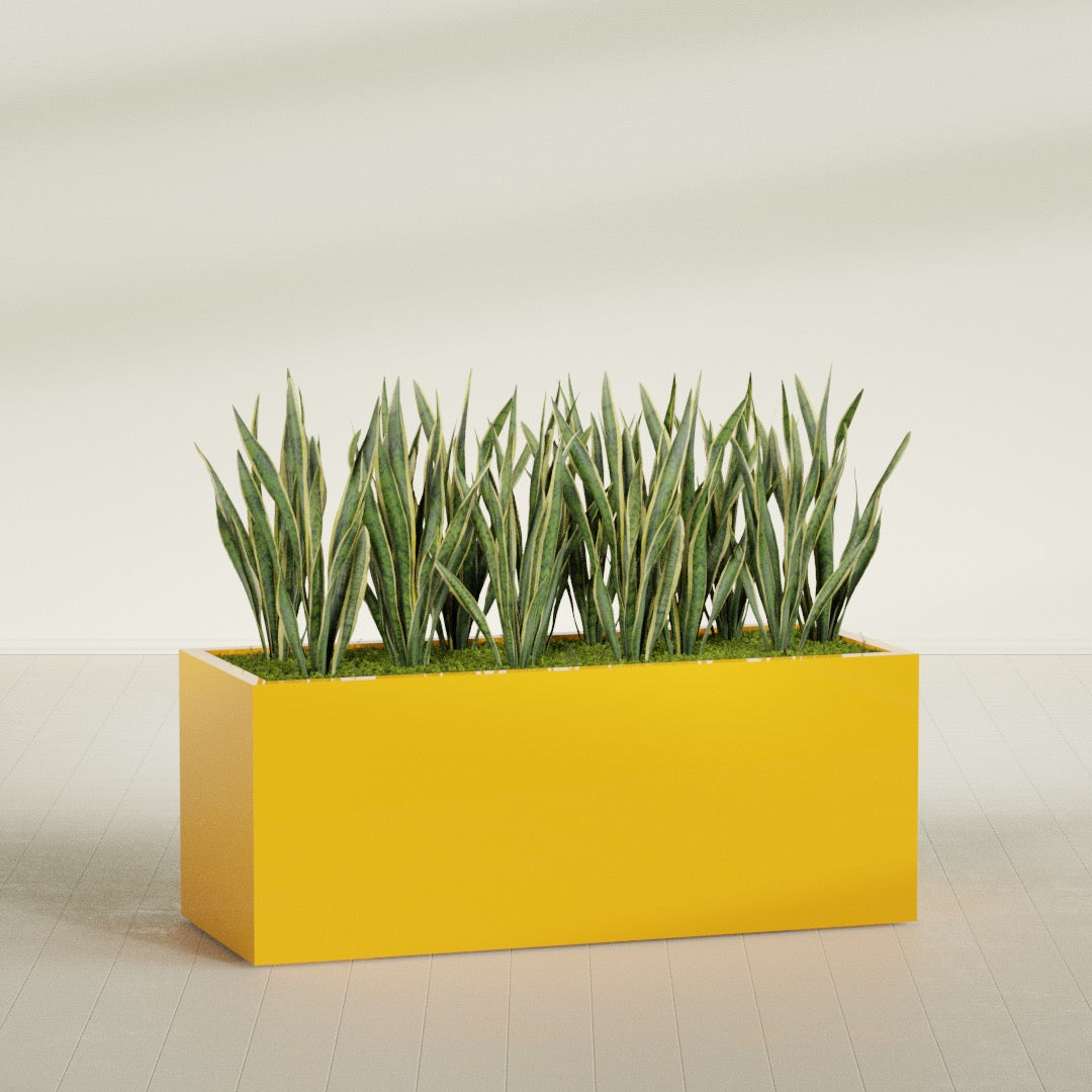 Granada rectangular fiberglass planter in Gloss Saffron, 60 × 24 × 24 in, shown planted in a room