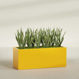 Granada rectangular fiberglass planter in Gloss Saffron, 60 × 24 × 24 in, shown planted in a room