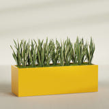 Granada rectangular fiberglass planter in Gloss Saffron, 72 × 24 × 24 in, shown planted in a room