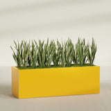 Granada rectangular fiberglass planter in Gloss Saffron, 72 × 24 × 24 in, shown planted in a room