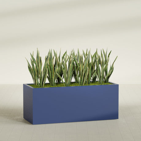 Granada rectangular fiberglass planter in Matte Cobalt Blue, 60 × 24 × 24 in, shown planted in a room