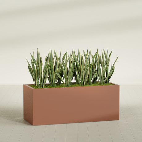 Granada rectangular fiberglass planter in Matte Terra Cotta, 60 × 24 × 24 in, shown planted in a room