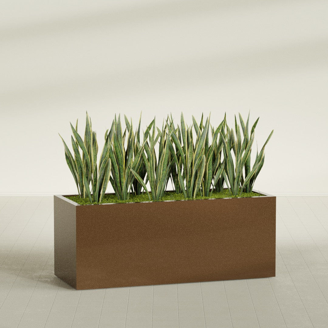 Granada rectangular fiberglass planter in Metallic Bronze, 60 × 24 × 24 in, shown planted in a room