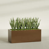 Granada rectangular fiberglass planter in Metallic Bronze, 60 × 24 × 24 in, shown planted in a room