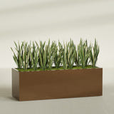 Granada rectangular fiberglass planter in Metallic Bronze, 72 × 24 × 24 in, shown planted in a room